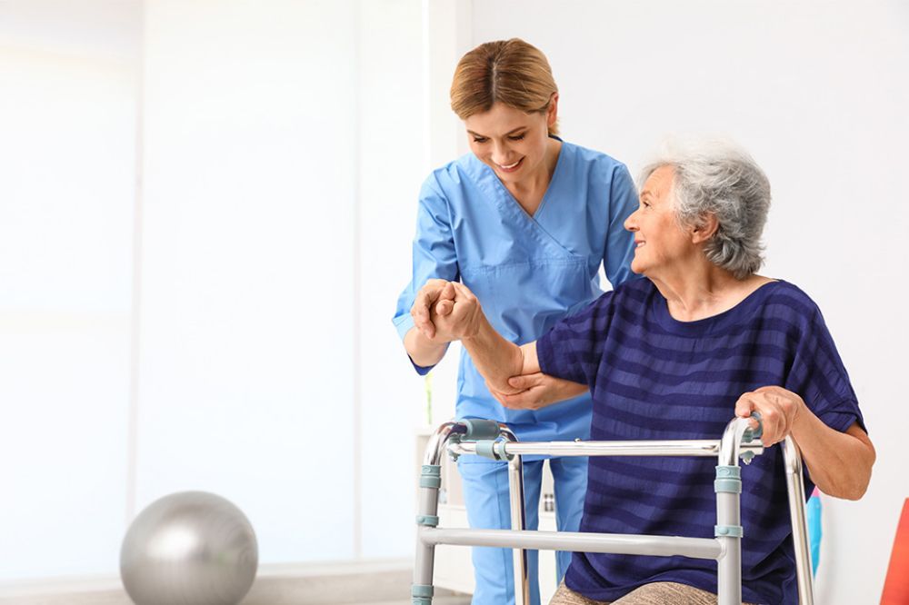 Pflegekraft hilft älterer Frau mit Gehhilfe